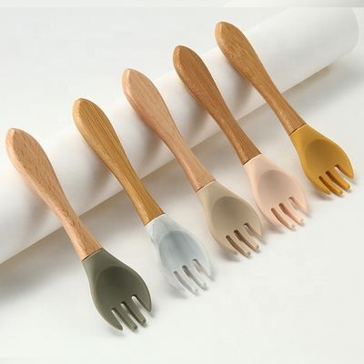 Produto as forquilhas e as colheres do silicone resistentes ao calor com punho de madeira
